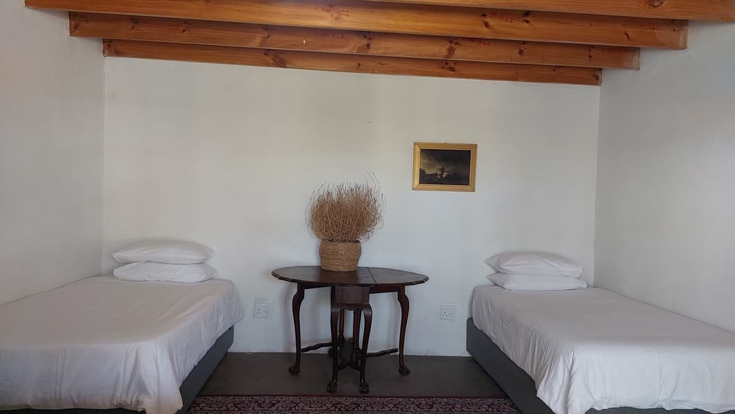 Twin beds and a round side table under a beamed ceiling