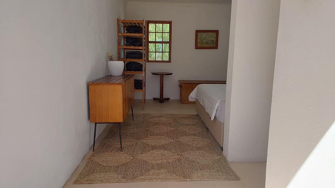 Flatlet bedroom with a pine sideboard and blanket shelves