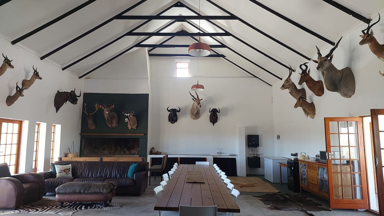 Trophy-lined hall at Hartsrust House with leather couches and a long dining table
